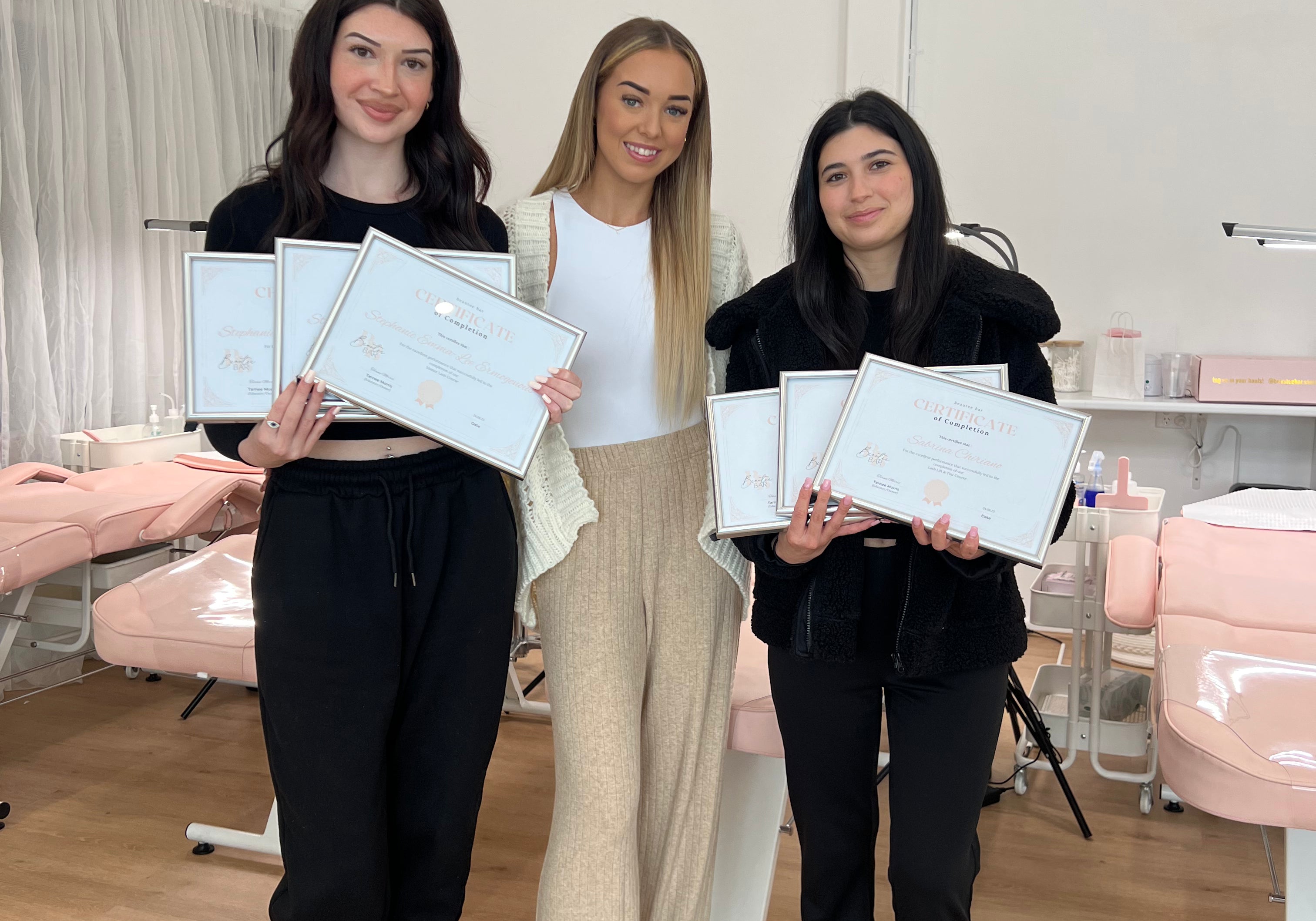 Two graduates proudly holding multiple certificates with their Lash and Brow Educator at By Tarnee Morris in Penrith, celebrating their achievements in professional lash and brow training courses.