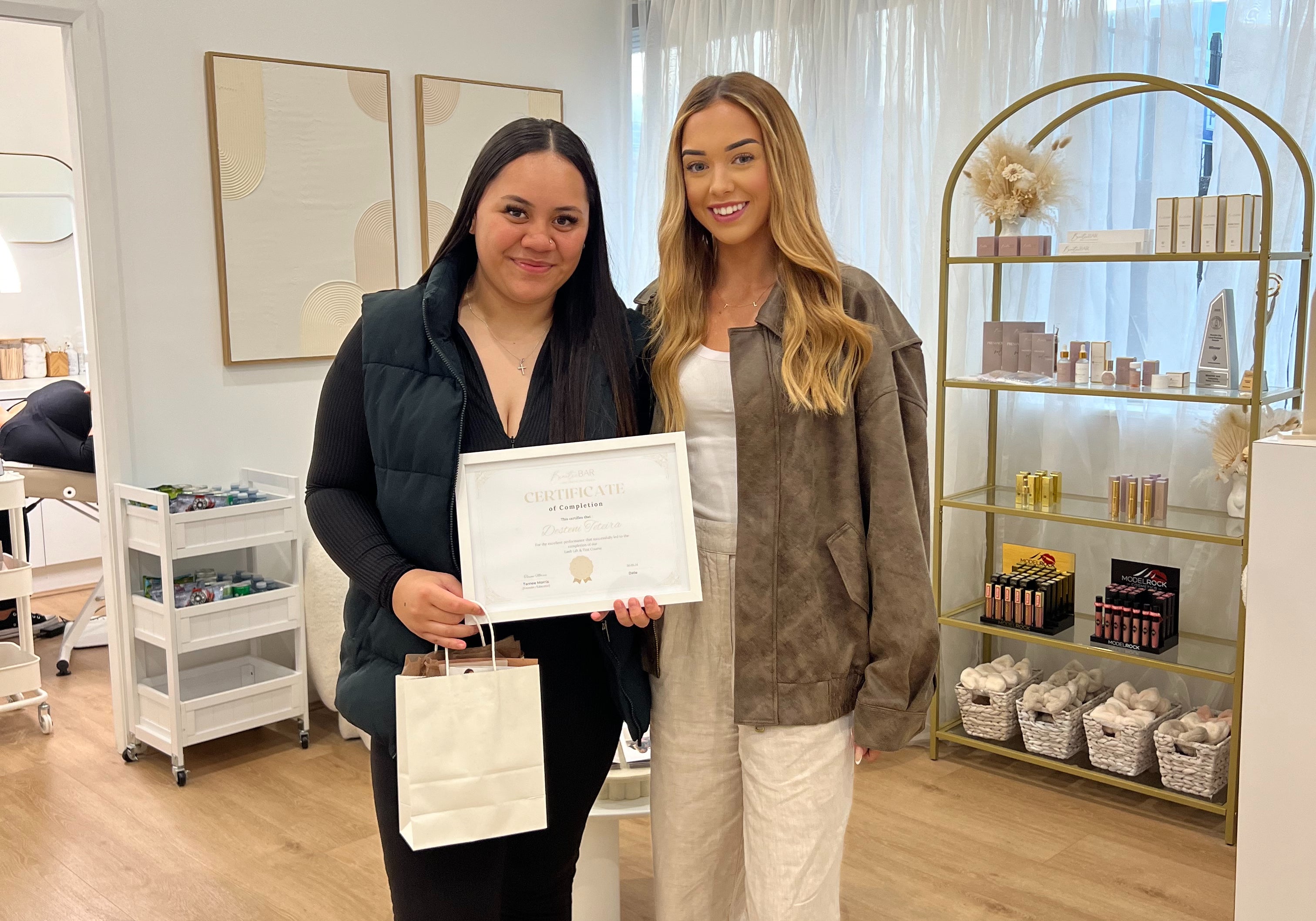 Graduate holding a certificate alongside a Lash and Brow Educator at By Tarnee Morris in Penrith, celebrating successful completion of a lash and brow training course in a professional beauty studio.